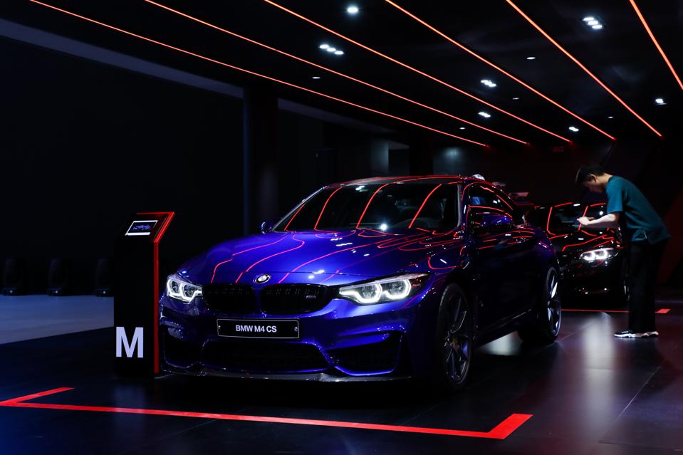 An attendee takes a photograph of a BMW M4 CS vehicle on display during the press day of the 2018 Busan International Motor Show. Photographer: SeongJoon Cho/Bloomberg