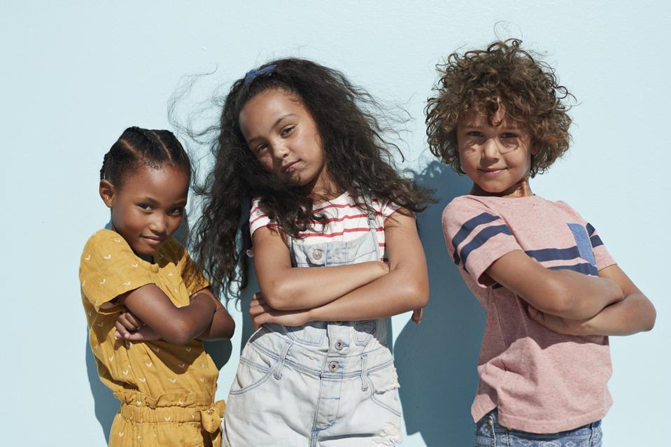 Portrait of 3 cool kids together on blue backdrop in summer