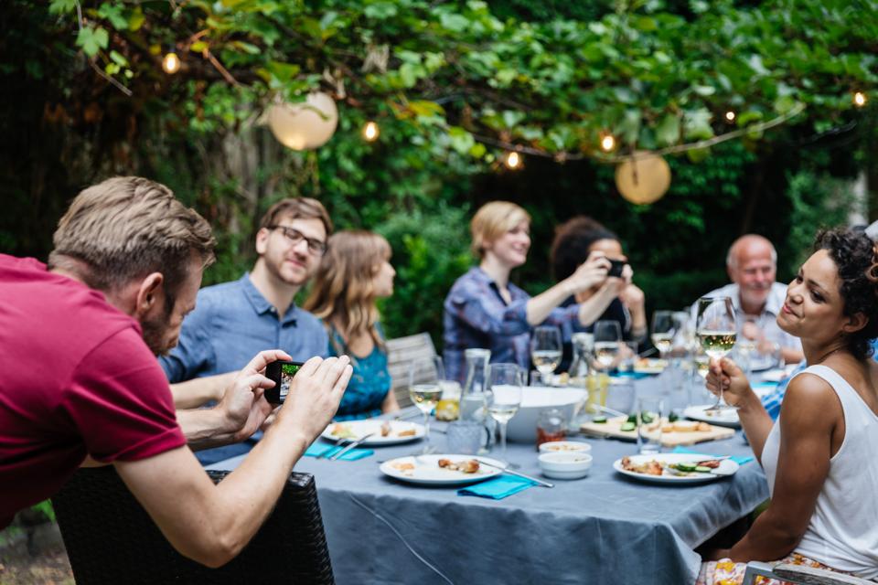 Man Taking Photo Of Friends At Family BBQ
