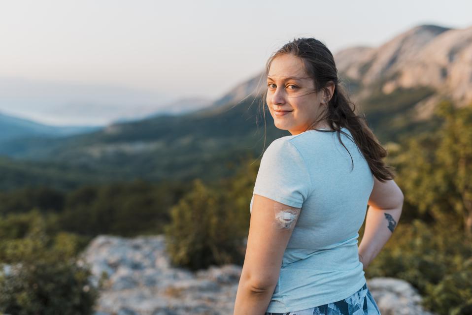 Woman with diabetes standing on top of the hill and looking at camera