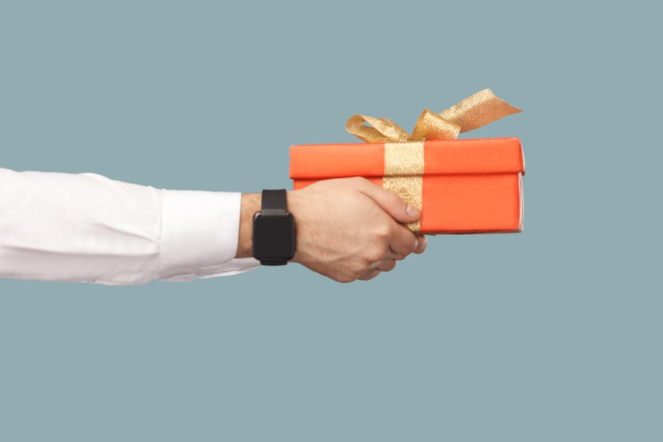 Business people concept, richly and success. human hand in white shirt with black smart watches holding red gift box with gold ribbon.