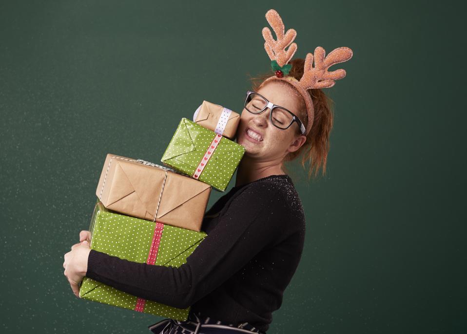 Funny woman carrying stack of heavy christmas gifts