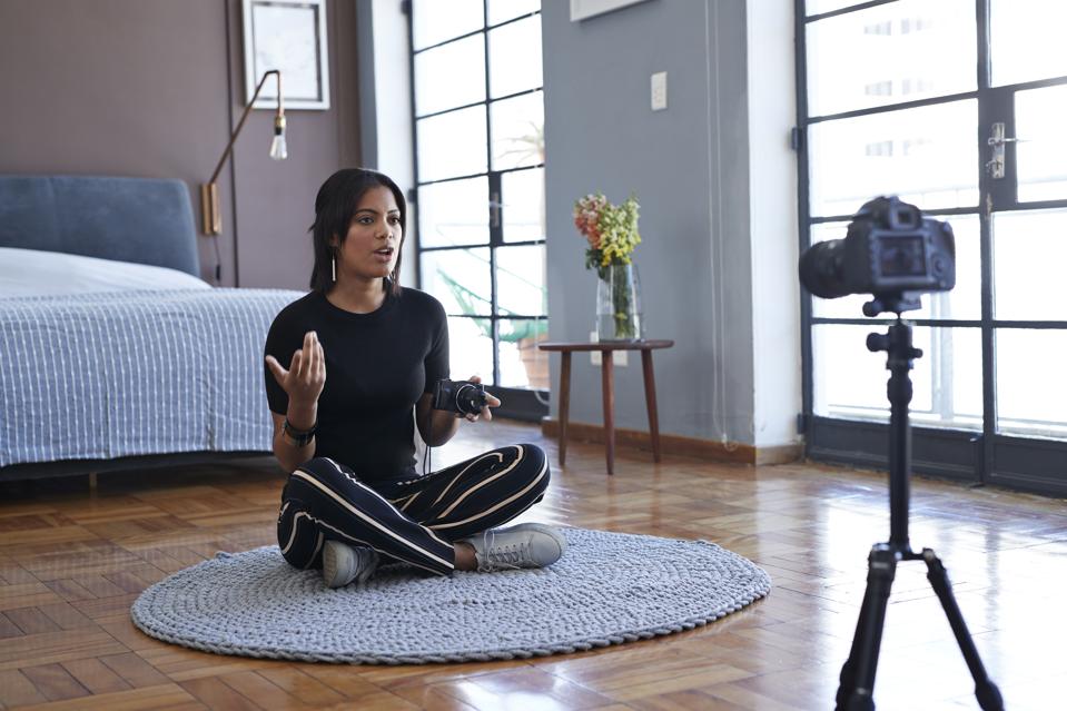Female influencer recording for video blog about pocket camera