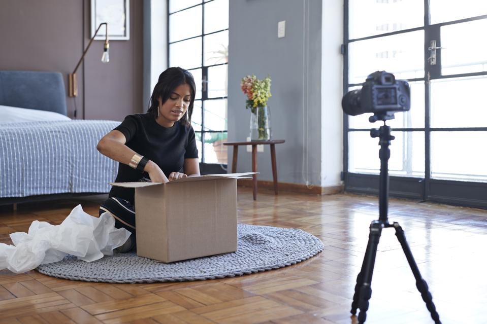 Female influencer doing ″unboxing″ video from home