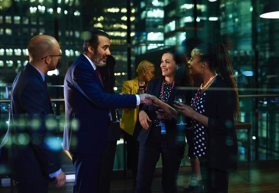 Businessman being introduced to female colleagues at evening event