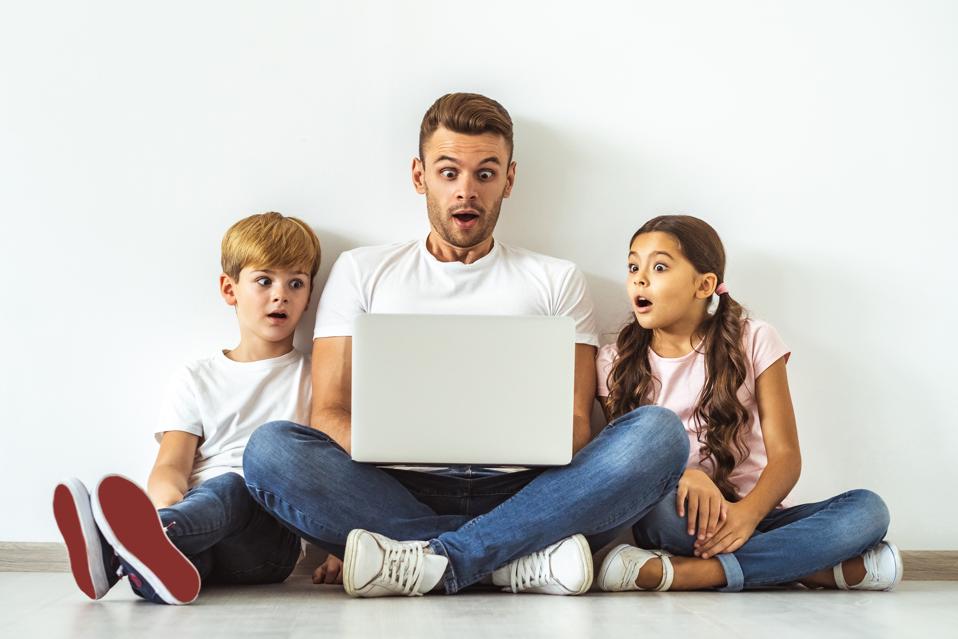 The surprised father and kids with a laptop sitting on the floor