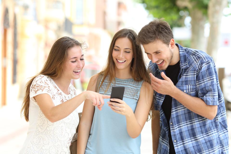 Friends watching smartphone content in the street