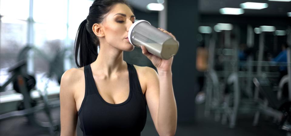 Sporty woman drinking protein shake after workout, muscle gain nutrition, health