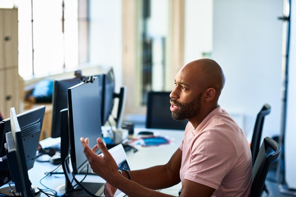 Serious businessman with beard at desk explaining
