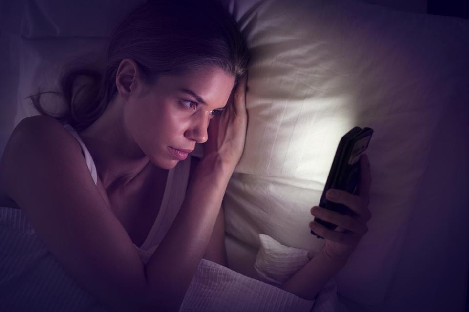 Young woman looking at smartphone in bed