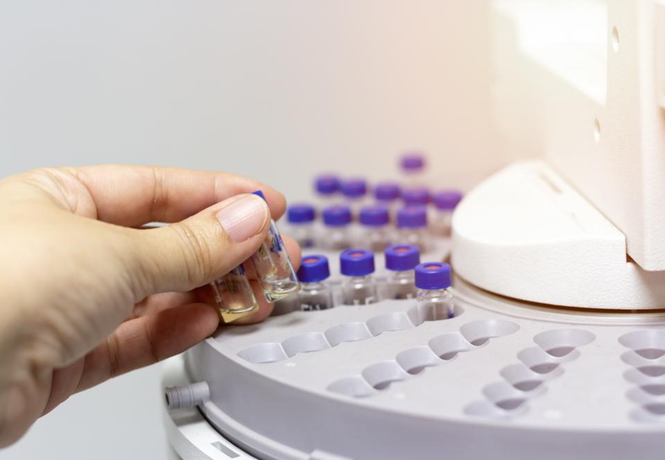 A scientist loads vials into a mass spectrometer. These machines can identify microplastics.