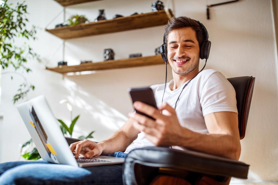 Someone smiling while listening to content on his smartphone.
