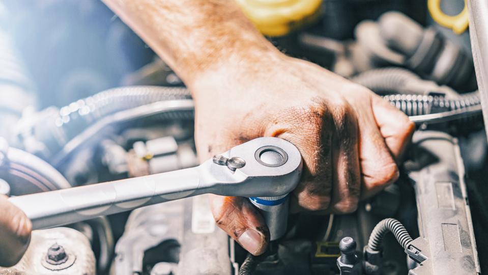 Hands of car mechanic with wrench in garage