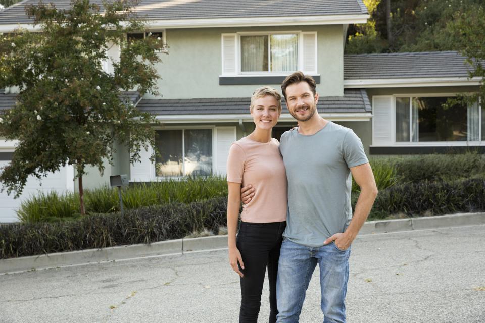 Portrait of smiling couple in front of their home