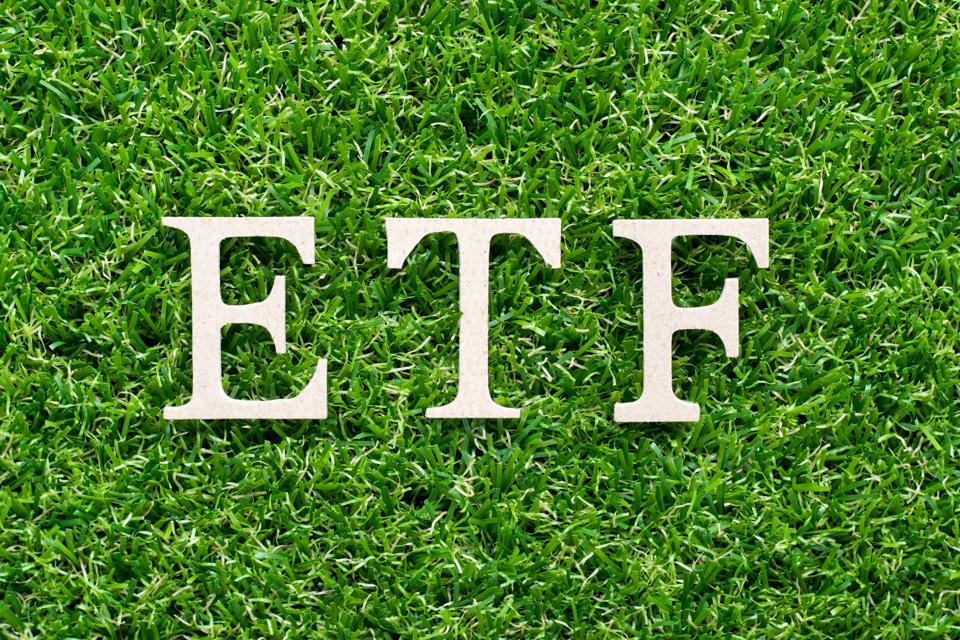 Wood alphabet in word ETF (abbreviation of Exchange Traded Fund) on artificial green grass background