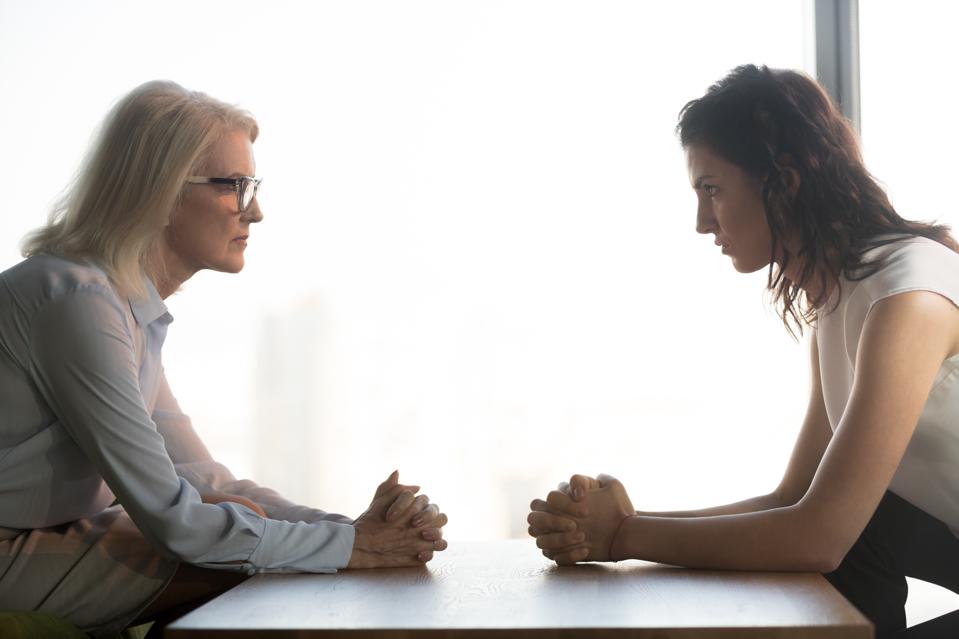 Young and old businesswomen sitting opposite, generations conflict at work