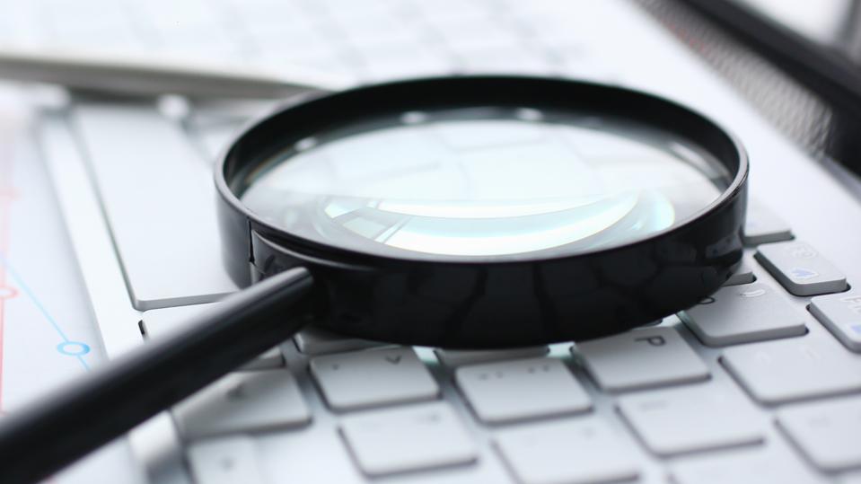 Magnifying glass lies on white keyboard on