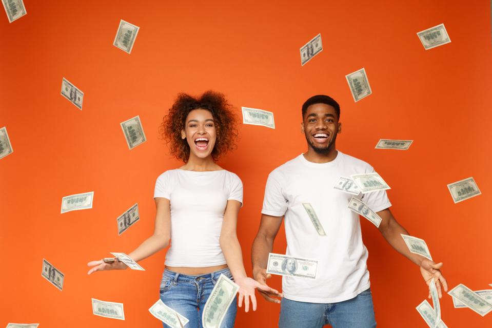 Young black couple standing under money banknotes shower