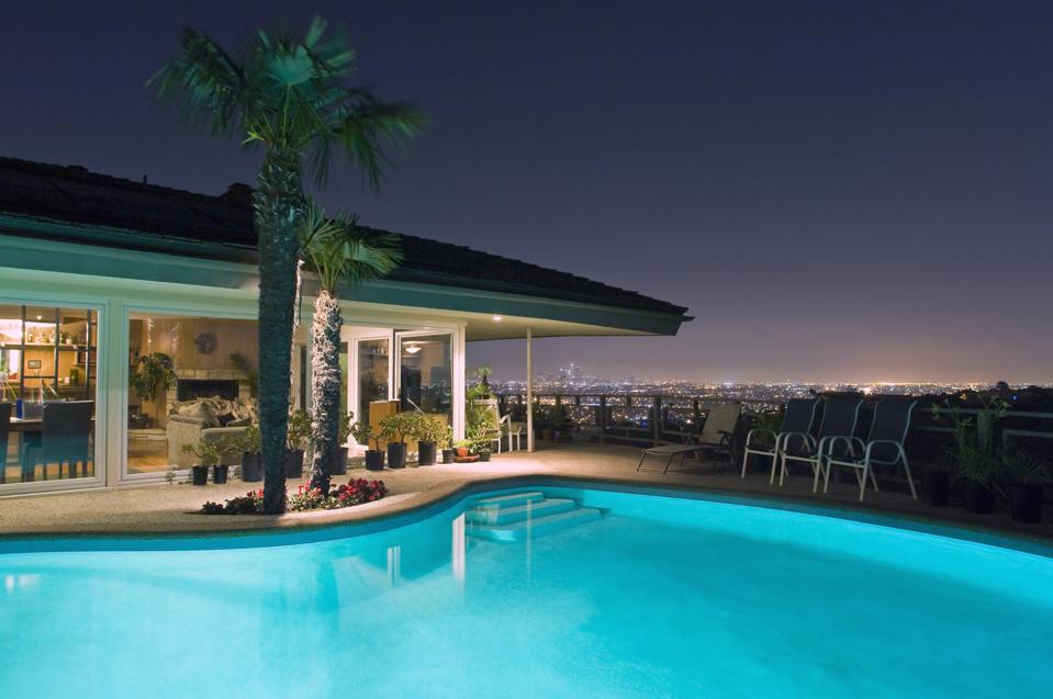 Homebuilder Shares Tips For First Time Home Buyers Illuminated pool at night with city in background, Los Angeles, California, United States