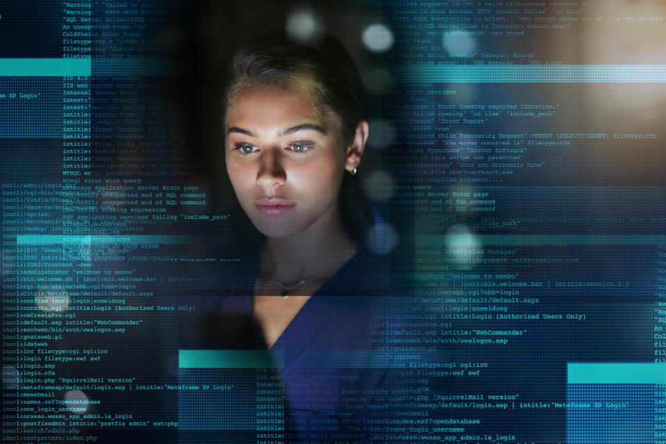 Shot of a young woman working on code during a late night at work