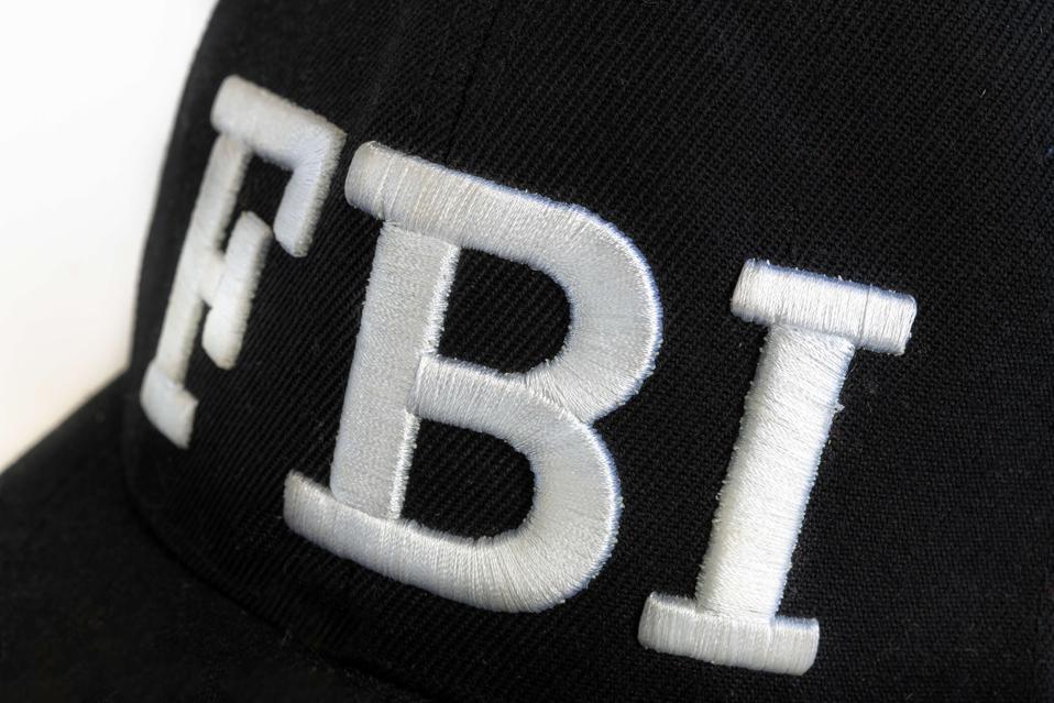 Close up of the FBI logo in white on a black cap.