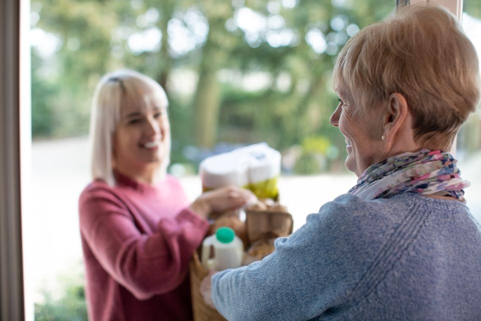 Female Neighbor Helping Senior Woman With Shopping