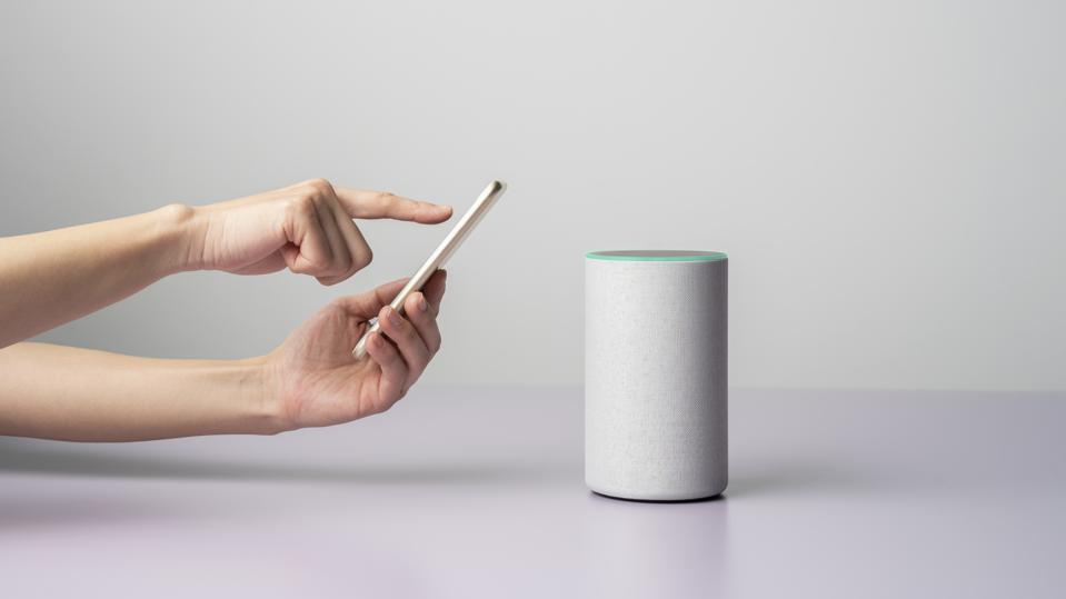 Woman using a Smart speaker with smart phone.
