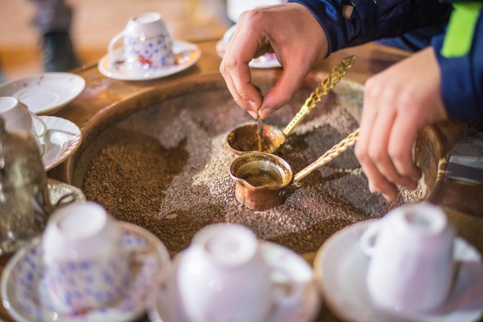 Closeup on hands brewing Turkish coffee in copper cezve pot, Istanbul, Turkey