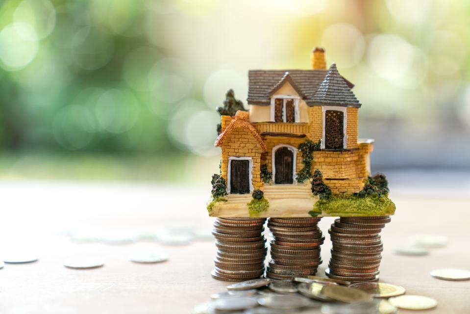 Close-Up Of Coins And Toy House On Table