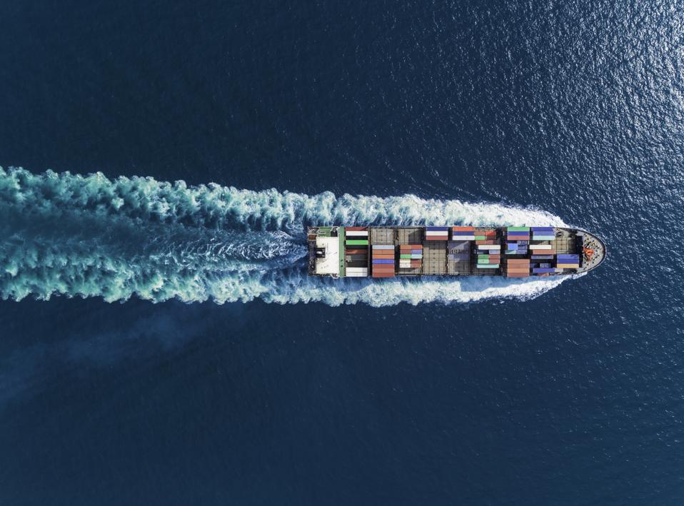 Aerial top view container ship full speed with beautiful wave pattern for logistics, import export, shipping or transportation.