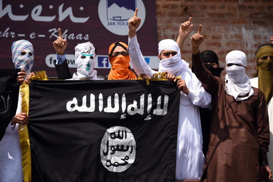 Kashmiri Protesters hold an ISIS flag while making gestures...