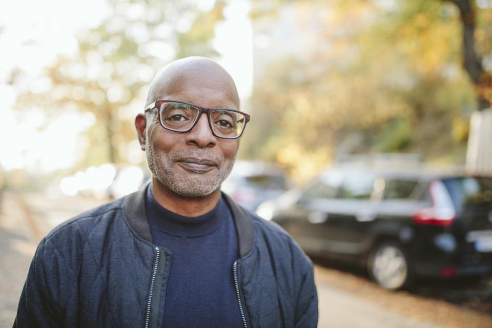 Portrait of smiling senior man standing on road