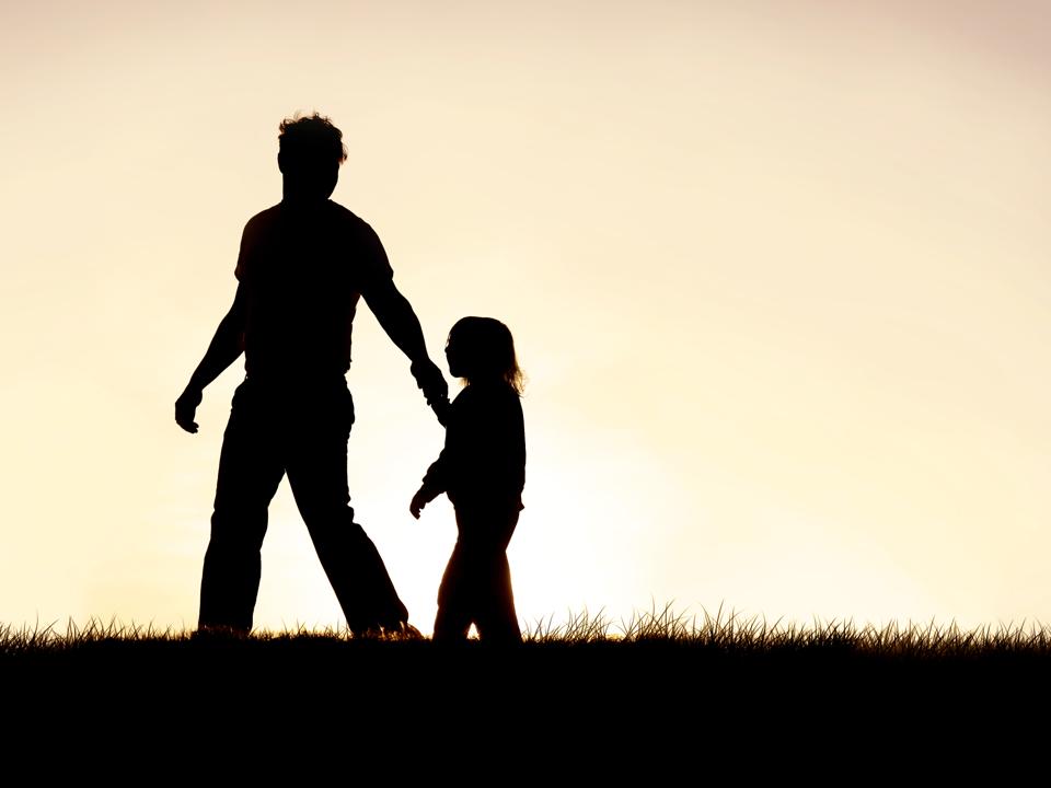 Dad and child on a walk as the sun is at the horizon.