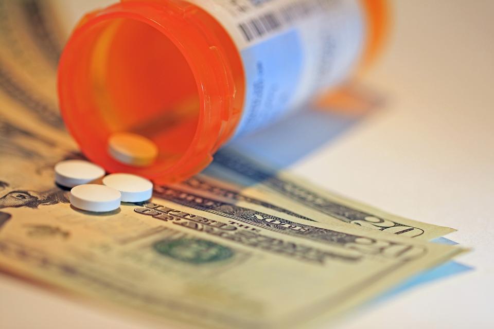 Prescription pill medication spilling out of container on American twenty dollar bills