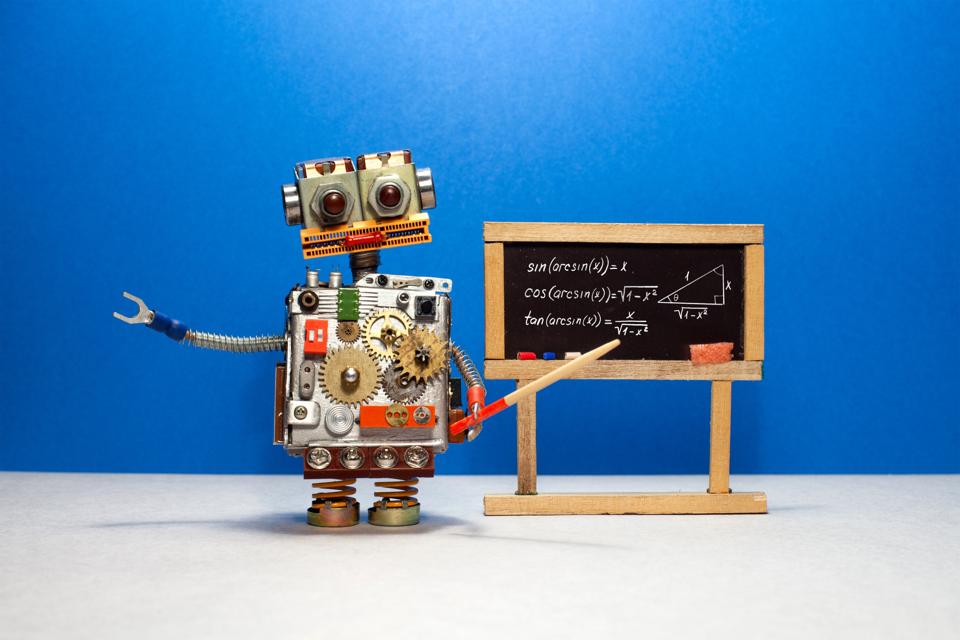 Artificial intelligence and trigonometry lesson in college. Robot teacher explains theory inverse trigonometric functions. Classroom interior with handwritten formula black chalkboard.