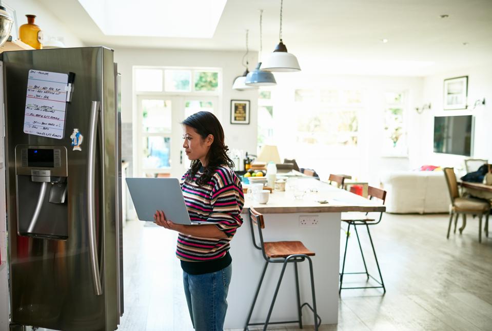 Woman using laptop by fridge and buying food online