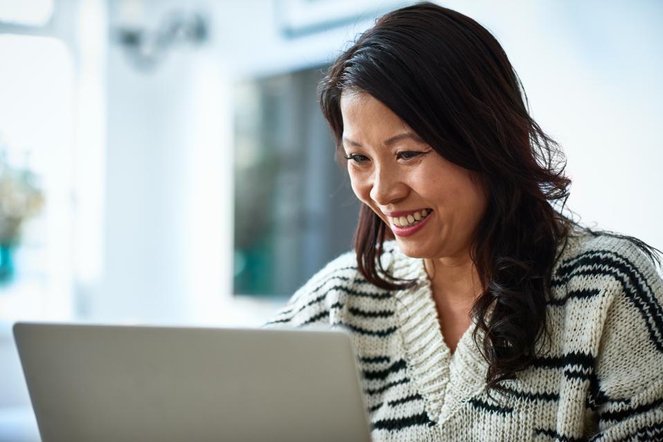 Mid adult woman using laptop and smiling