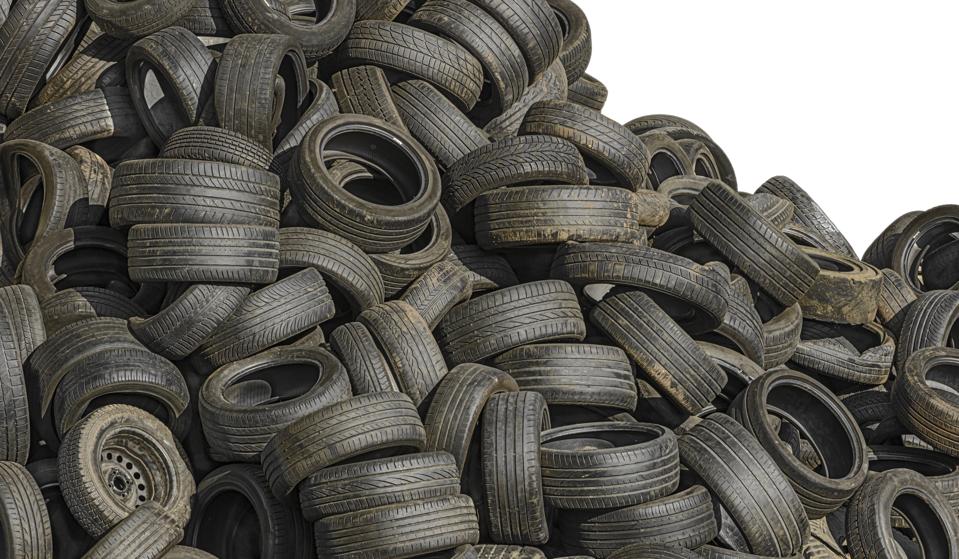 Recycling: Pile of old used scrap tyres at junkyard, isolated