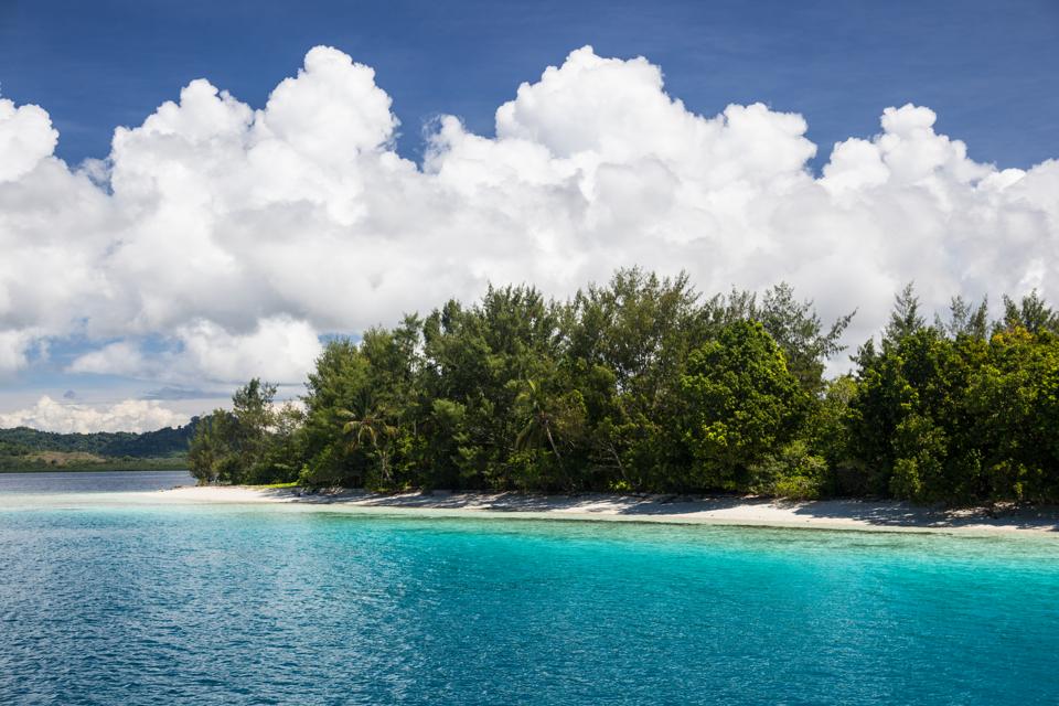 Bright sunlight shine on a remote beach and colorful lagoon in the Solomon Islands.