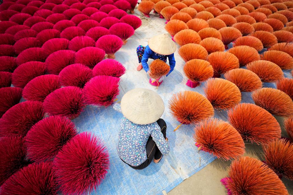 Two Vietnamese women surrounded by bouquets of incense sticks