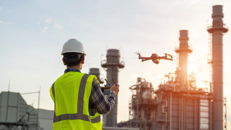 Construction worker piloting drone at a building site. Drones provide video surveillance or industrial inspection.