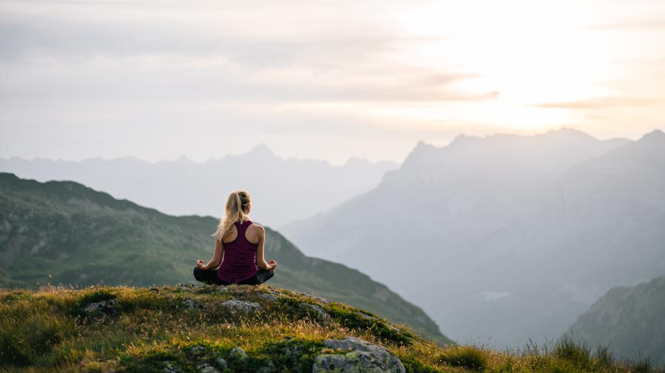 Woman performs yoga moves on mountain summit