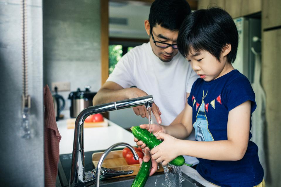 Father and son washing Fresh fruit in kitchen sink