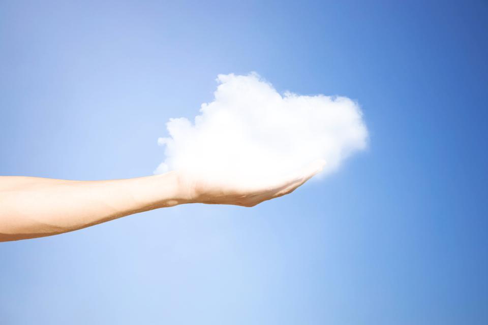 Creative picture of fluffy cloud sustained by human hand.