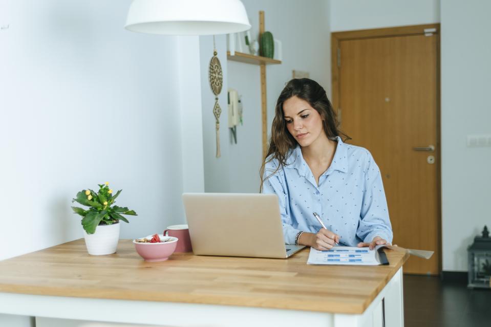 Young woman using laptop during breakfast at home