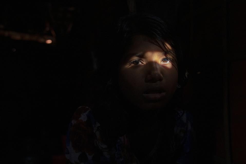 Portrait of a Rohingya girl siting in her makeshift tent at...