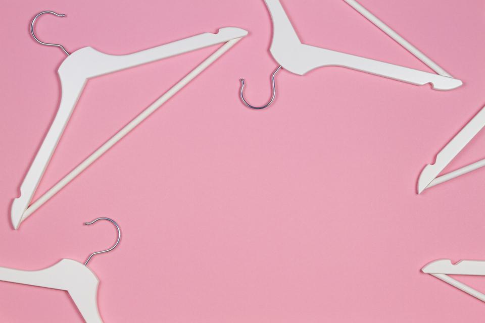 White wooden clothes hangers on pastel pink background. Shopping, sale, promo, social media, new season concept