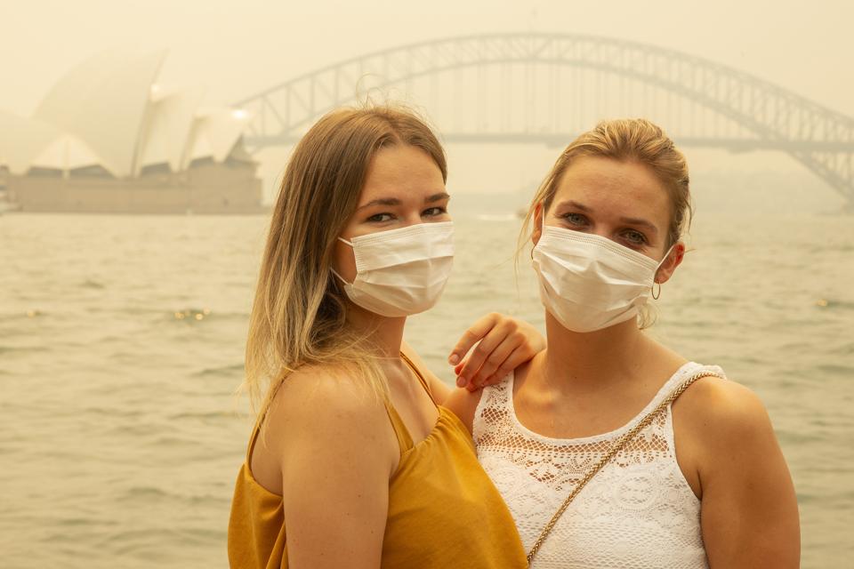 German tourists Julia Wasmiller, left, and Jessica Pryor pose for a photo while wearing face masks December 19 in Sydney.