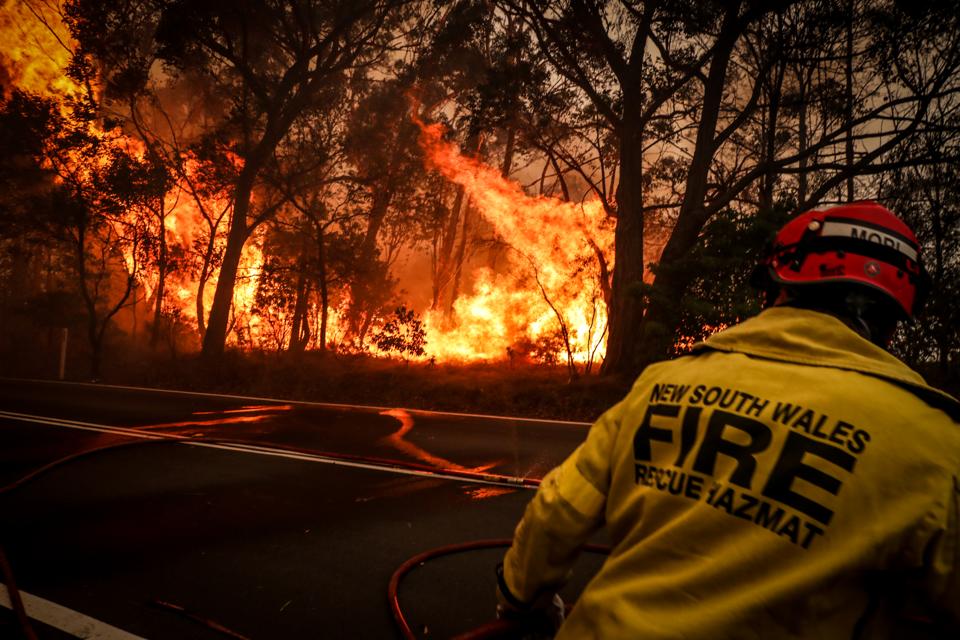 A firefighter run from a bushfire burning on the outskirts of the town of Bilpin on December 19 in Sydney, Australia.