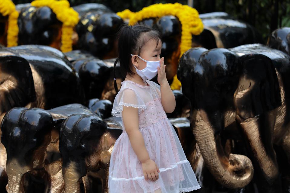 Chinese girl wearing a protective face mask stands near the...